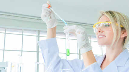 close up face of female scientist holding a tube and beaker with liquid substance. woman research is working in the Laboratory.