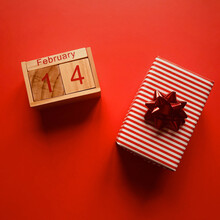 Directly Above Shot Of Gift Box And Wooden Calendar On Red Background