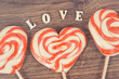 Inscription love and sweet funny lollipop in shape of heart on board. Surprise for birthday, valentine or different occasions