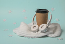 A Cup Of Coffee Wrapped In A Scarf On A Blue Background With Snowflakes.