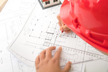 Blueprint designer wearing red hard hat at work