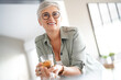 © goodluz - Cheerful 50-year woman drinking hot tea at home