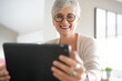 © goodluz - Cheerful mature woman with eyeglasses using digital tablet