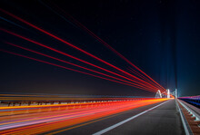 Light Traces Of Cars Driving Along The Road At Night Through A Beautiful Modern Highway Bridge