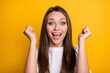 Photo portrait of excited girl with raised fists isolated on bright yellow colored background