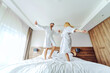 © Dusan Petkovic - A cheerful middle-aged couple in bathrobes celebrating their anniversary in a hotel at weekend. They are jumping on the bed.
