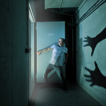 Scared Man With Shadow On Wall Standing In Darkroom