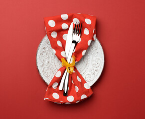 Wall Mural - white round ceramic plates, fork with knife on a red background, top view. Table setting, copy space