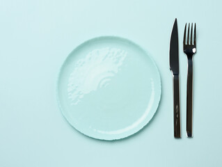 Wall Mural - round ceramic plates, fork with knife on a green background, top view