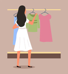 Girl chooses clothes on the hanger on shopping. Female buyer is selecting clothes in a store. Young beautiful fashion girl is standing near the stand with clothes. Shopper during the sale in a shop