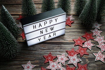 Wall Mural - Happy New Year word in light box with Christmas tree decoration on wooden background