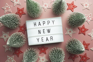 Wall Mural - Happy New Year word in light box with Christmas tree top view on pink background