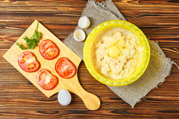 grated potato sliced red tomatoes two eggs on a wooden table. cooking potato pancakes. top overhead