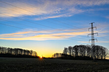 Sunrise Over Field With Power Line In Sky