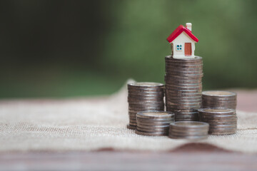 Wall Mural - Minature houses resting on coin stacks, concept for property ladder, mortgage and real estate investment