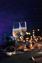 Canvas Print - Christmas card two glasses of champagne on a neon colored background with a garland