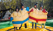 © JackF - Portrait of happy adult friends having fun posing in inflatable sumo suits at outdoor amusement park