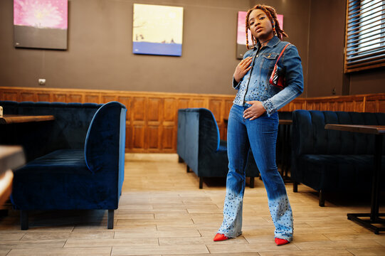 Lovely african american woman with dreadlocks in blue stylish jeans jacket at cafe. Beautiful cool fashionable black young girl indoor.
