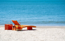 Empty Orange Beach Chair With Outdoor Bag And A Glass Of Martini On Tropical Island Beach With Beautiful Nature Of Blue Sea In Summer Sunny Day. Tourist Hotel Resort And Holiday Vacation Concept
