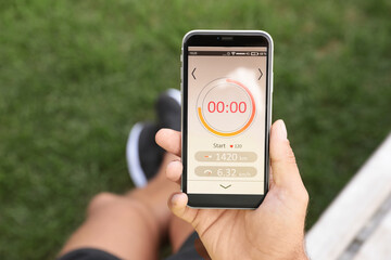 Man using fitness app on smartphone outdoors, top view