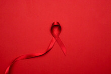Cancer Ribbons. Red Ribbon Symbol In Hiv World Day On Dark Red Background. Awareness Aids And Cancer. Flat Lay, Top View, Copy Space