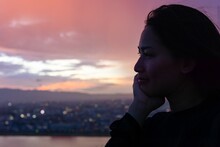 Close-up Of Thoughtful Young Woman Looking Away Against Sky At Sunset
