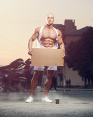 Portrait of young fitness man with cardboard at street