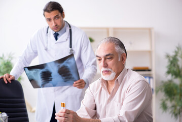 Wall Mural - Young male doctor and old patient in antismoking concept