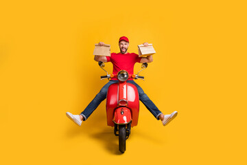 Canvas Print - Photo of careless crazy guy drive bike hold two packages wear red t-shirt cap jeans isolated yellow color background