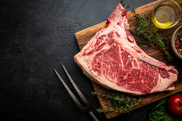 Wall Mural - Raw fresh meat T-bone beef Steak and butcher knife on black background, top view