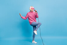 Full Length Photo Portrait Of Woman Standing On One Leg Singing Holding Microphone In One Hand Isolated On Pastel Blue Colored Background