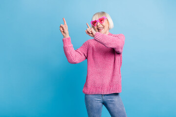 Wall Mural - Photo portrait of cheerful old lady wearing rose-tinted glasses dancing isolated on pastel blue colored background