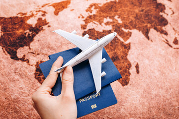 Hand holding NEUTURAL passport on the world map background with model airplane / travel concept / selective focus