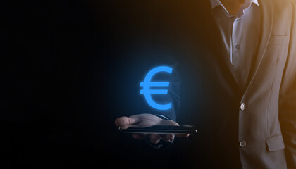 Businessman holds money coin icons (EUR or Euro) on dark tone background..Growing money concept for business investment and finance