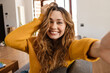 © Drobot Dean - Cheerful beautiful girl smiling and taking selfie while resting on couch