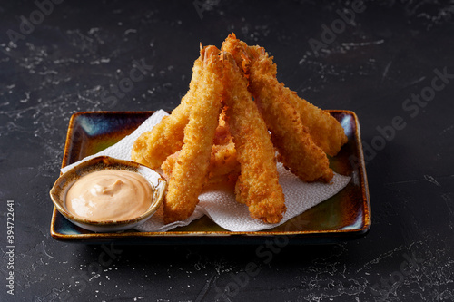 Fotografía Tempura deep-fried EBI prawns with spiced sauce on a plate on a dark background