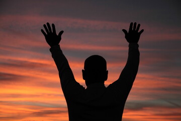 Wall Mural - praying to god with arms outstretched in the sky sunset stock photo