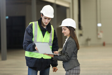 Wall Mural - Portrait of a female factory manager in a white hard hat and business suit and factory engineer in work clothes. Controlling the work process in the helicopter manufacturer.	