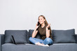 © F8  \ Suport Ukraine - Beautiful happy woman on a white sofa making a phone call isolated on white background