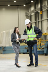 Wall Mural - Portrait of a female factory manager in a white hard hat and business suit and factory engineer in work clothes. Controlling the work process in the helicopter manufacturer.	