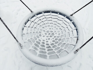 The round swing seat is covered in snow