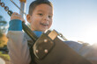 © Brayden Howie/Austockphoto - Cute mixed race three year old boy playing on a swing in a suburban playground