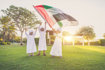 Wall Mural - Children playing together in Dubai in the park. Group of kids wearing traditional kandura white dress from arab emirates