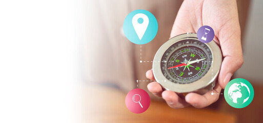 Banner of hand holding magnetic compass banner representing concept of traveling vacation holiday adventure exploring finding places location to go, with graphics icon white background copy space