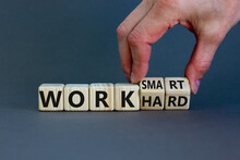 Work hard or work smart. Hand turns cubes and changes the words 'work hard' to 'work smart'. Beautiful grey background. Business and work smarter concept, copy space.