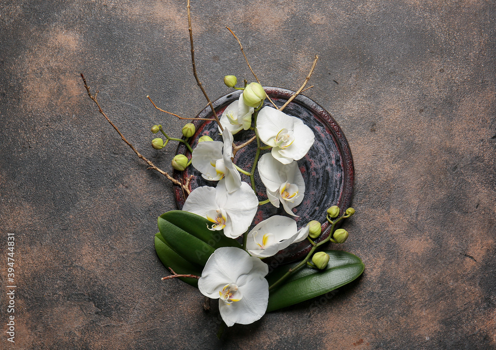 Plate with beautiful orchid flowers on grunge background