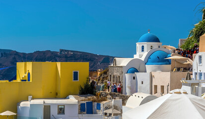 Wall Mural - A view across of the village of Oia, Santorini towards blue roof churches in summertime