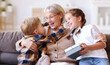© JenkoAtaman - Excited grandmother hugging grandchildren with gift.