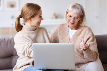 Wall Mural - Cheerful mother and daughter using laptop together.