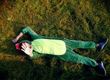 High Angle View Of Man In Green Mascot Lying On Land